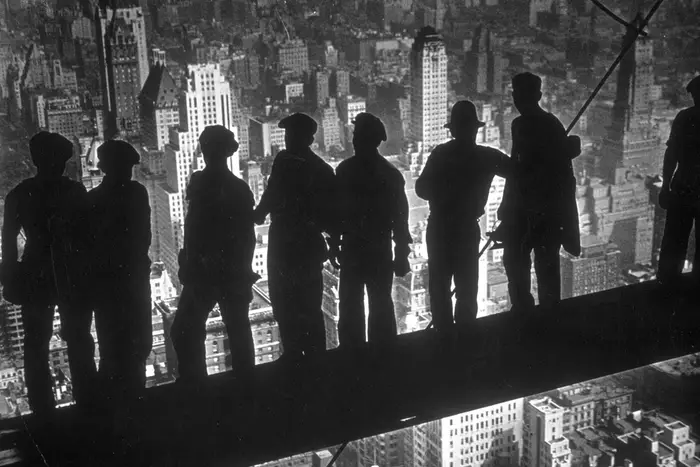 A group of steel workers standing on scaffolding 70 storeys high looking down over New York City from the RCA building, 1938.